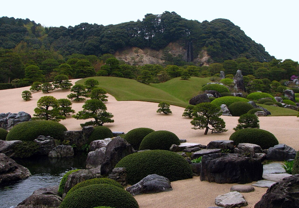 足立美術館枯山水庭與被借景的山 —— 遠方崖面上細細的白線，是人工開鑿的龜鶴瀑布