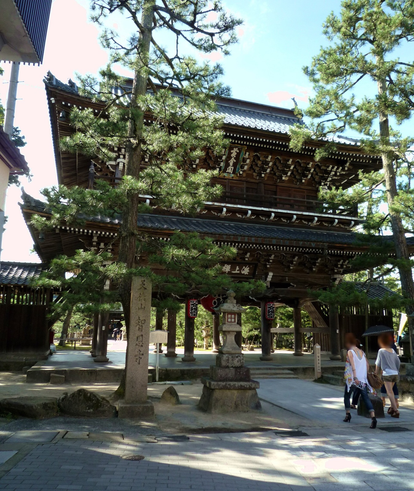 智恩寺的山門（俗稱黃金閣）—— 禪宗樣式的三間三戶二重門，前方有松樹與刻著「天橋山 智恩寺」的石柱
