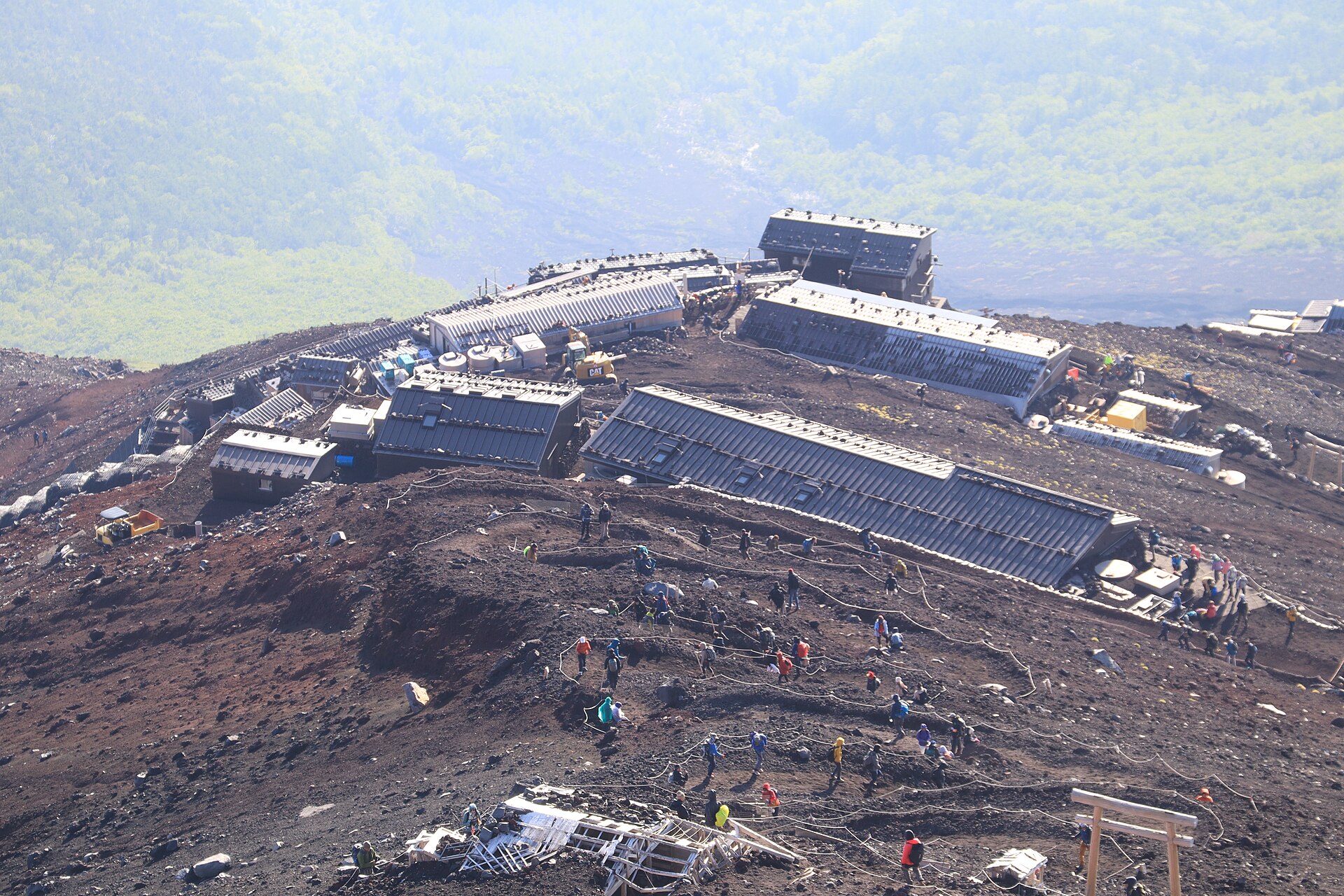 富士山吉田路線上排隊前進的登山者與沿途的山屋，山坡呈現紅褐色火山礫地形