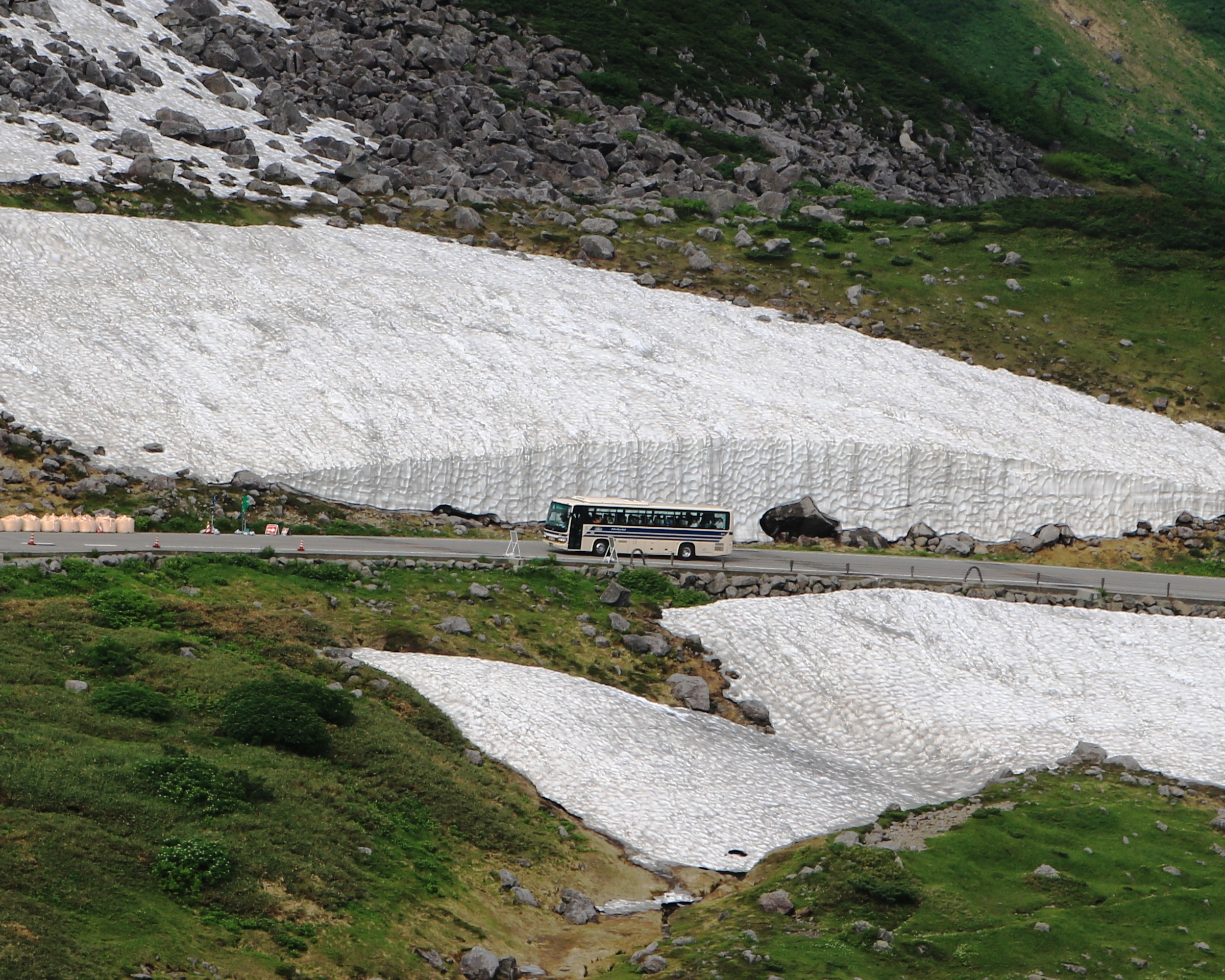 立山黑部 雪之大谷（雪の大谷）— 道路兩側高聳的雪壁與行駛中的高原巴士
