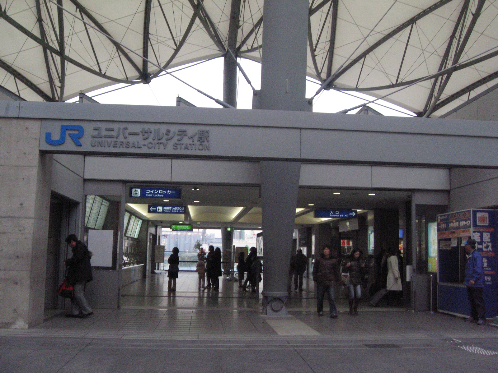 ユニバーサルシティ駅改札口外的「JR ユニバーサルシティ駅 UNIVERSAL-CITY STATION」站名標識與帳篷狀鋼構屋頂——前往大阪環球影城 USJ 的門戶車站