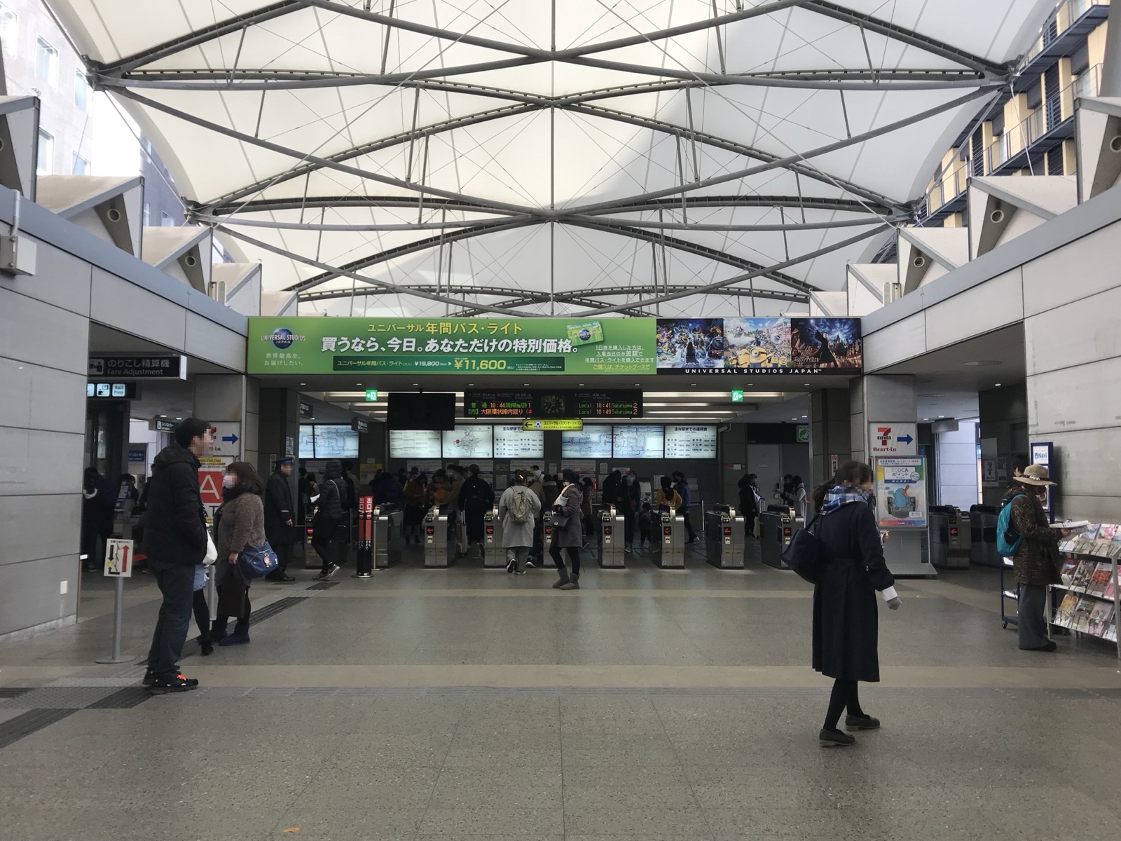 ユニバーサルシティ駅站內改札口（剪票口）區域——挑高的帳篷狀屋頂與寬敞的售票・閘門空間，旅客往來其間