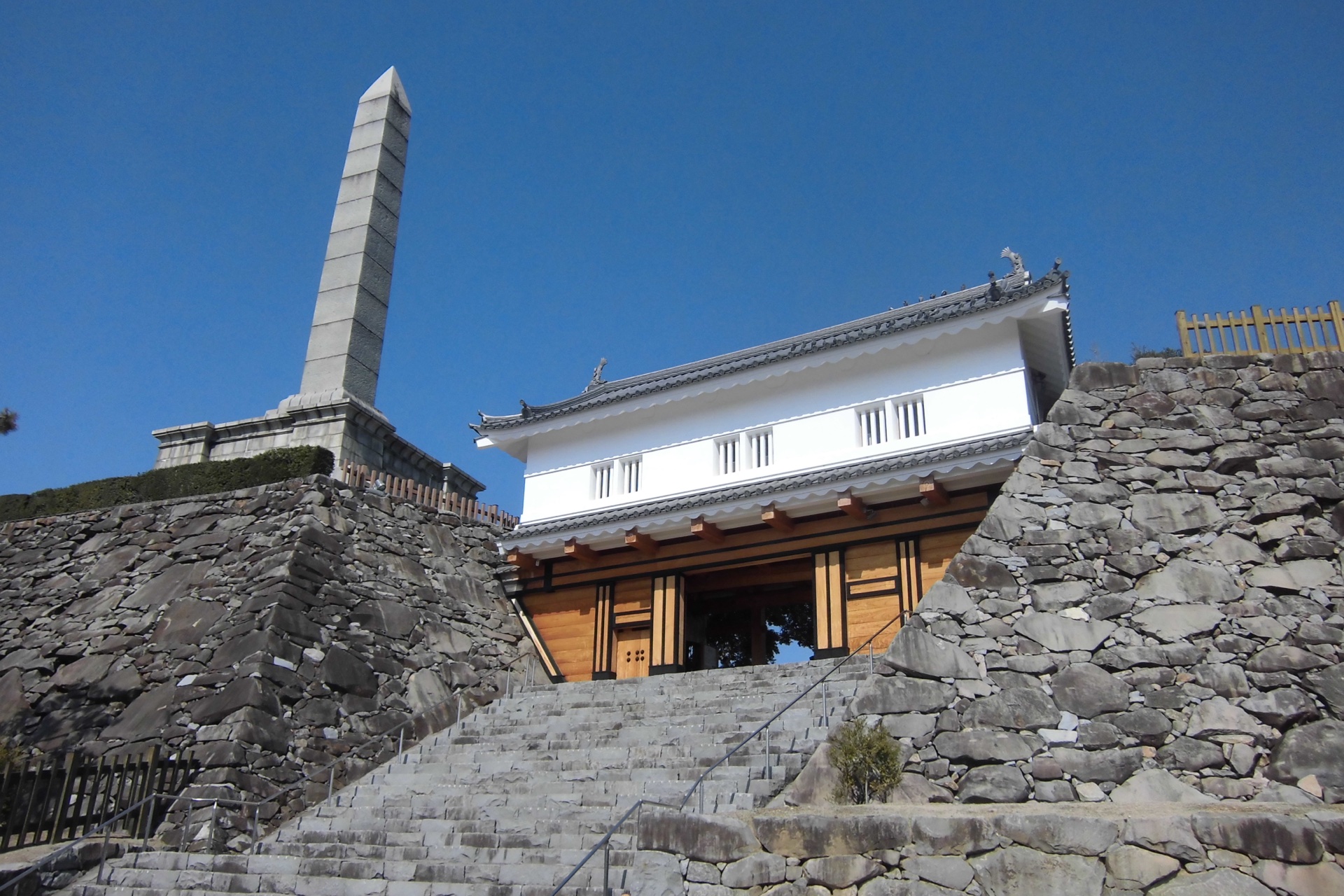 甲府城（舞鶴城）鉄門（くろがねもん）——木造復元門扉前方是護城河與石垣，市中心可見的城郭景觀